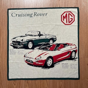 Może przedstawiać: Kremowa kwadratowa tkanina z zieloną obwódką przedstawiająca dwa samochody z otwieranym dachem, napis "Cruising Rover" i logo MG. Specyfikacje techniczne są wymienione pod samochodami. Tkanina ma około 40 cm x 40 cm.