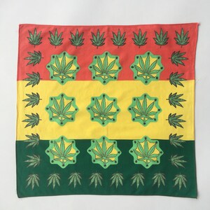May include: A square bandana in red, yellow, and green. The design includes repeating patterns of green cannabis leaves and starbursts. The edges are lined with smaller cannabis leaf motifs. The overall design is symmetrical.