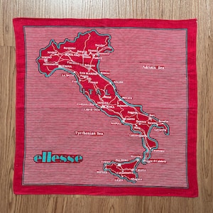 May include: Red and white striped bandana featuring a map of Italy with cities labeled in white and a turquoise outline. The word "ellesse" is printed in turquoise at the bottom.