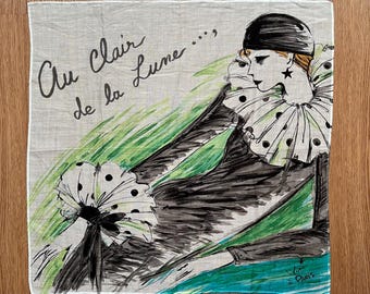 May include: A white handkerchief with a watercolor illustration of a figure in a black outfit with a polka-dot collar and fan. The text "Au Clair de la Lune..." is written in black script. The illustration is set against a green and blue background.