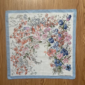 Puede incluir: Un pañuelo de color azul y blanco con estampado floral y el texto "J. MANOLO BORROMEO" en la esquina inferior derecha.