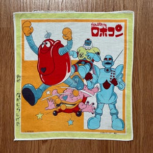 Puede incluir: Pañuelo cuadrado y vintage con una colorida ilustración de robots de dibujos animados. Los robots son de color rojo, azul, amarillo y rosa, con texto japonés. El fondo es una mezcla de amarillo y blanco.