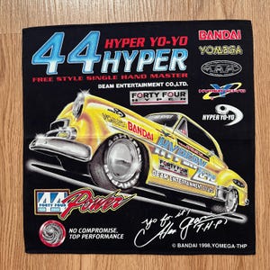 May include: Black square fabric with a yellow hot rod car graphic, the text "HYPER YO-YO" and "44 HYPER". It also features "FREE STYLE SINGLE HAND MASTER" and brand names. The fabric has a "Power" logo and the text "Yo for it!"