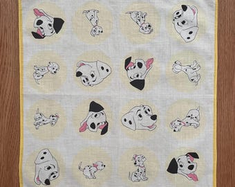 Peut inclure: Un mouchoir carré blanc cassé avec une bordure jaune. Le mouchoir présente un motif répété de chiens dalmatiens de dessin animé dans diverses poses, chacun dans un cercle jaune clair. Le texte "© MCMLX WALT DISNEY PRODUCTIONS" est imprimé en bas.