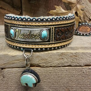 Puede incluir: Un collar de perro de cuero marr&oacute;n con una placa de nombre plateada que dice "Theodore". El collar est&aacute; decorado con piedras turquesa y tachuelas plateadas. Un amuleto plateado a juego con una piedra turquesa est&aacute; unido al collar.