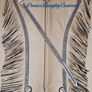 Puede incluir: Chaps de cuero color canela con flecos, bordados azules y plateados, piedras turquesa y el texto "Denice Langley Custom".