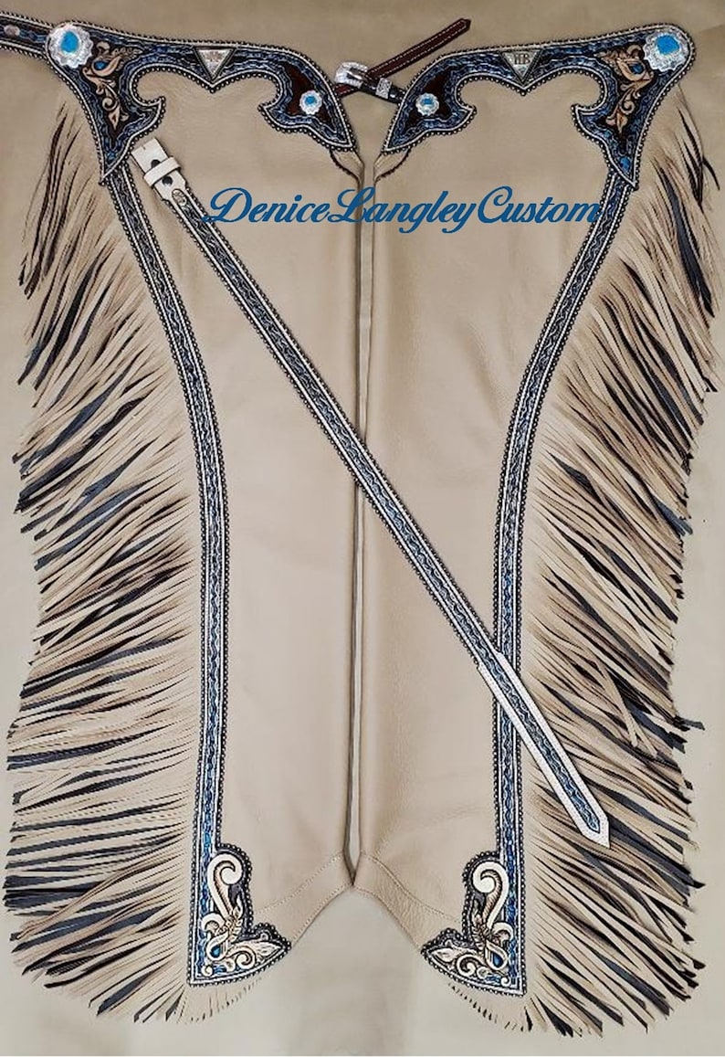 Puede incluir: Chaps de cuero color canela con flecos, bordados azules y plateados, piedras turquesa y el texto "Denice Langley Custom".