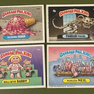 May include: Four Garbage Pail Kids trading cards. The cards feature grotesque cartoon characters with names like "Basking Robin," a melting ice cream cone with a face, and "Farrah Fossil," a skeleton. Other cards include "Bullseye Barry" and "Nailed Neil."