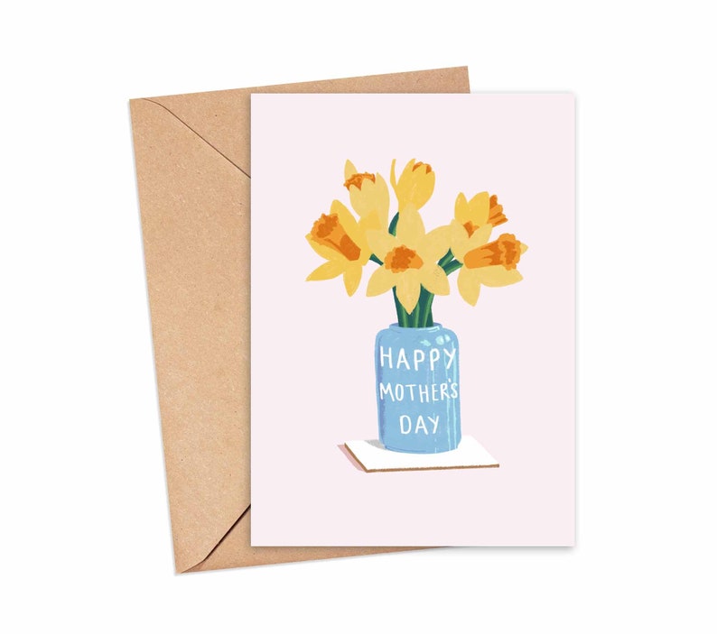 May include: A greeting card with a pink background featuring a blue vase with yellow daffodils. The vase has the text "Happy Mother's Day" written on it.