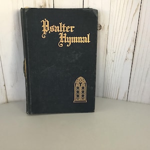 May include: A black Psalter Hymnal book with gold lettering and a gold decorative window design.