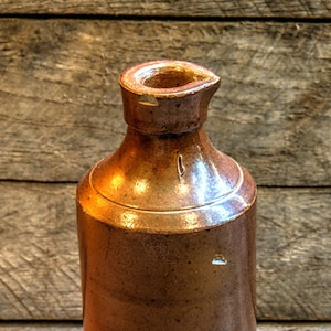 Può includere: Una bottiglia di terracotta marrone con un'ampia apertura e un'etichetta che recita "Vitreous Stone Bottles J. Bourn & Son Patentees Denby Pottery Near Derby I. & J. Arnold London England".