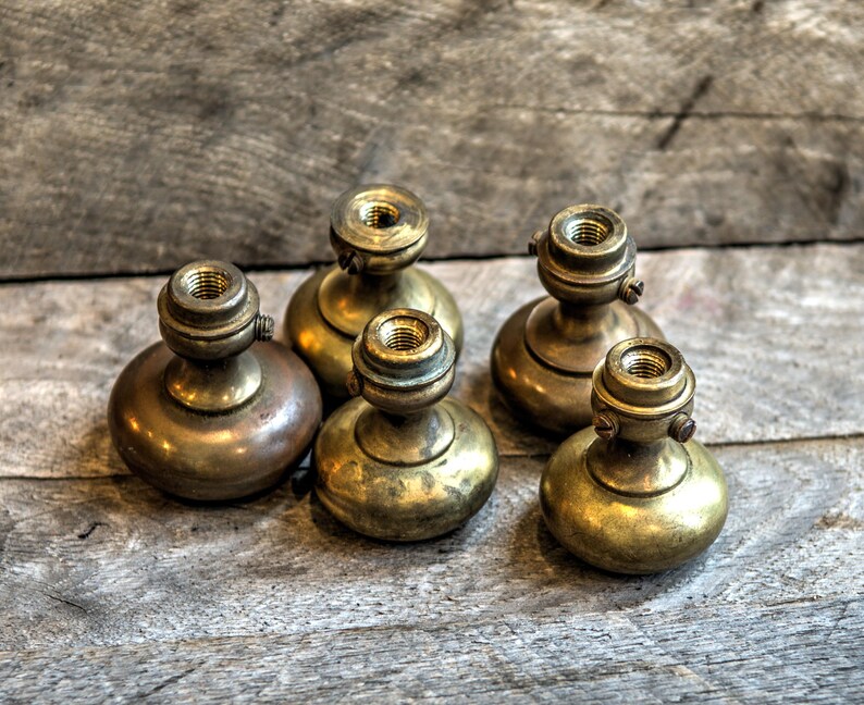 May include: Five antique brass door knobs with a rounded top and a threaded base. The knobs have a worn, aged finish.