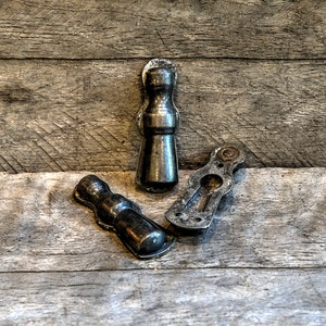 May include: Three antique metal door hardware pieces, including a door knob, a door pull, and a door latch. The pieces are all made of a dark metal and have a worn, aged look.