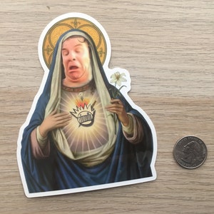 May include: A sticker of a woman in a blue robe with a crown of thorns and a heart with a cartoon face on it. The woman is holding a white flower.
