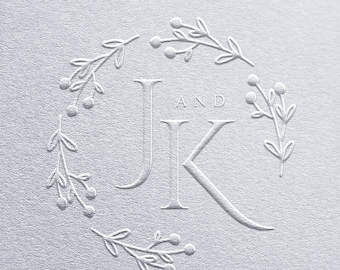 May include: A textured, silver-colored design featuring the initials "JK" in a serif font, with "AND" above. The initials are surrounded by a wreath of delicate leaves and berries, creating an elegant, embossed effect.