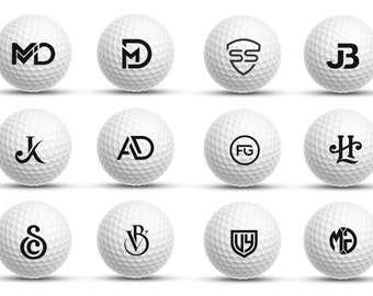 Könnte beinhalten: Zwölf weiße Golfbälle mit schwarzen Buchstabeninitialen auf jedem Ball. Die Initialen sind: MD, SS, JB, K, AD, FG, H, S, VB, WY und MG.