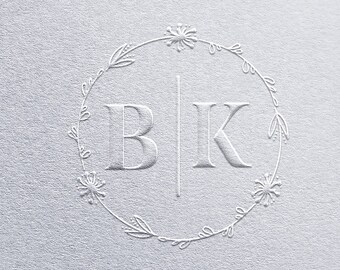 May include: A white embossed design featuring the letters "BK" separated by a vertical line, encircled by a floral wreath. The design is set against a textured, off-white background, creating a subtle, elegant aesthetic.