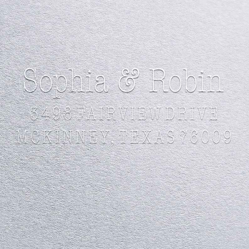 K&ouml;nnte beinhalten: Wei&szlig;er Pr&auml;gedruck auf grauem Hintergrund mit dem Text "Sophia & Robin 3498 Fairview Drive McKinney, Texas 76009"