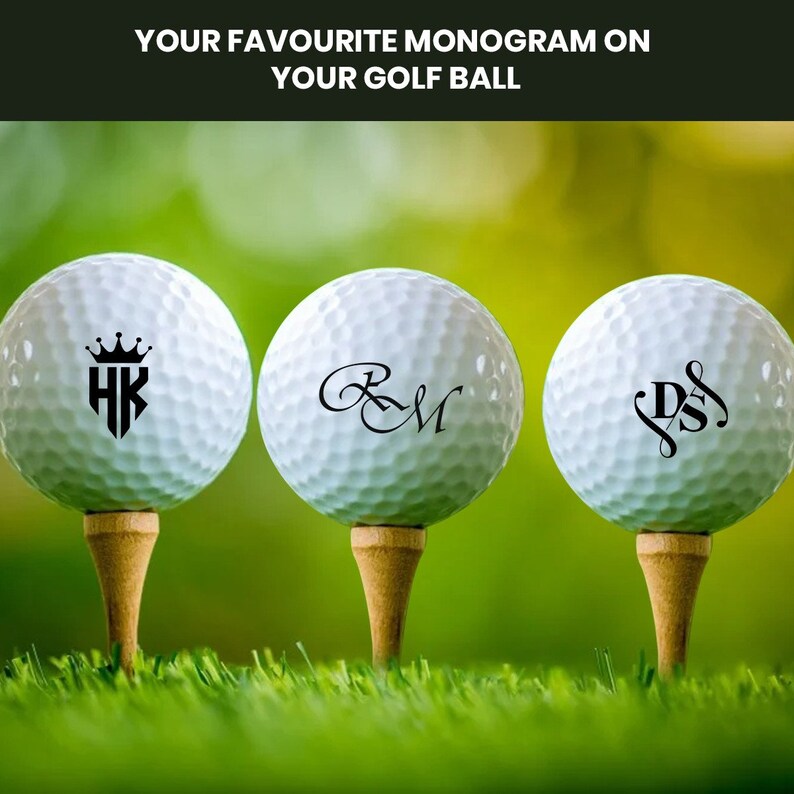 K&ouml;nnte beinhalten: Drei wei&szlig;e Golfb&auml;lle mit schwarzen personalisierten Monogrammen. Die Monogramme sind "HK" mit einer Krone &uuml;ber den Buchstaben, "R&M" in einer kursiven Schrift und "DS" mit einer dekorativen Verzierung.