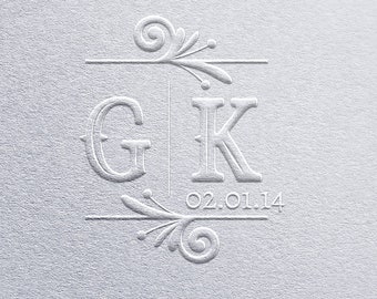 May include: A textured, light gray surface with an embossed design. The design features the letters "G" and "K" with a decorative border and the date "02.01.14" below. The overall aesthetic is elegant and classic.