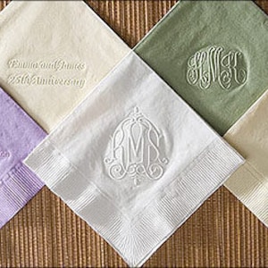 May include: Five different colors of paper napkins with embossed designs. The napkins are folded in half and have a white border. The designs include a monogram, a wedding anniversary message, and a floral design.