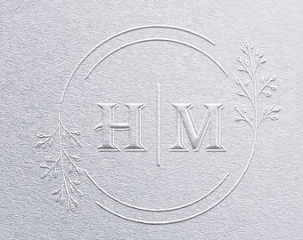 May include: A white monogram with the letters "H" and "M" in a circle with a double line border. The letters are separated by a vertical line. There are two small floral designs on either side of the monogram.