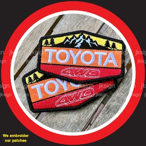 May include: Two embroidered patches with a mountain scene and the text "TOYOTA 4WD" in white on a red, orange, and yellow background.
