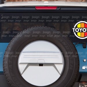 Peut inclure: Un Toyota FJ Cruiser bleu avec une roue de secours &agrave; l'arri&egrave;re. La voiture a un logo "TOYOTA" avec un cercle rouge, orange et jaune sur la vitre arri&egrave;re. La voiture a &eacute;galement un embl&egrave;me "FJ CRUISER" &agrave; l'arri&egrave;re.