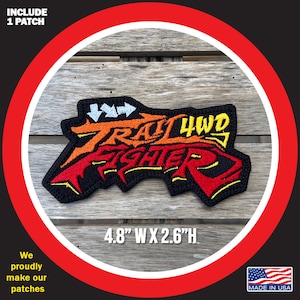 May include: A black embroidered patch with the text "Trail 4WD Fighter" in red, orange, and yellow lettering. The patch is 4.8 inches wide and 2.6 inches high.