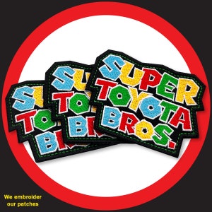 May include: Four embroidered patches with the text "Super Toyota Bros!" in different colors. The patches are black with green, red, yellow, and blue stitching.