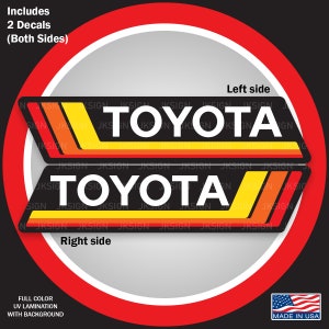 May include: Two black and white "TOYOTA" decals with orange and yellow stripes. The decals are on a white background with a red circle around them. The text "Includes 2 Decals (Both Sides)" is at the top of the image. The text "Left side" and "Right side" are below the decals. The text "FULL COLOR UV LAMINATION WITH BACKGROUND" is at the bottom left of the image. The text "MADE IN USA" is at the bottom right of the image.