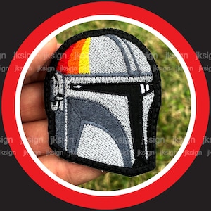 May include: A gray and black embroidered patch of a Mandalorian helmet with a red, orange, and yellow stripe across the top.