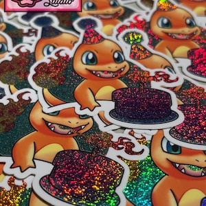 May include: A close-up of a stack of holographic stickers featuring a cartoon character wearing a party hat. The character is orange and has a large, toothy grin. The stickers are covered in iridescent glitter.