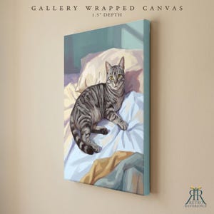 May include: A gallery wrapped canvas with a 1.5 inch depth featuring a digital painting of a grey tabby cat with yellow eyes resting on light blue and white bedding. The artwork displays soft shadows and highlights, capturing the cat in a relaxed pose.