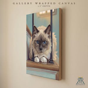 May include: A gallery wrapped canvas with a 1.5 inch depth featuring a digital illustration of a fluffy, cream and brown colored cat with bright blue eyes sitting on a wooden staircase behind dark vertical railings in a soft indoor setting.