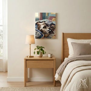 Puede incluir: Una impresi&oacute;n de arte mural rectangular con la pintura de un gato marr&oacute;n y blanco tumbado boca arriba dentro de una maleta abierta llena de ropa doblada. El gato tiene marcas oscuras en la cara y las orejas, en un dormitorio.