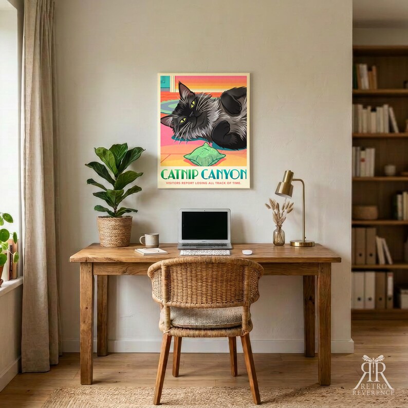 K&ouml;nnte beinhalten: Ein rechteckiges Wandposter mit einem schwarzen Katzenmotiv, die auf einem bunten Boden mit einem gr&uuml;nen Kissen liegt. Der Text lautet CATNIP CANYON und VISITORS REPORT LOSING ALL TRACE OF TIME. Das Poster h&auml;ngt an einer Wand &uuml;ber einem Holztisch.