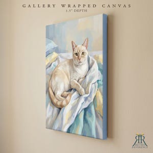 May include: A gallery wrapped canvas with a 1.5 inch depth featuring a painting of a cream-colored cat resting on soft, light blue and white bedding. The artwork displays a feline with pointed ears and light fur, rendered in a painterly style.