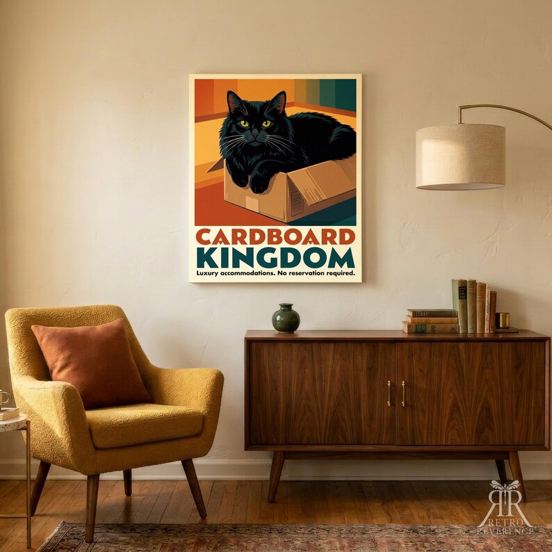 May include: A rectangular wall art print featuring a black cat sitting inside a brown cardboard box. The text reads CARDBOARD KINGDOM and Luxury accommodations. No reservation required. The background has colorful vertical stripes.