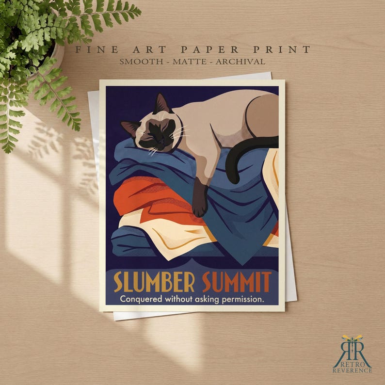 May include: A fine art paper print featuring a Siamese cat sleeping on a stack of folded blankets in shades of blue, orange, and cream. The text reads SLUMBER SUMMIT and Conquered without asking permission. The print has a smooth matte finish.