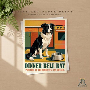 May include: A fine art paper print featuring a black and white border collie sitting in a kitchen next to a metal bowl. The text reads DINNER BELL BAY and PUNCTUAL TO THE SOUND OF A CAN OPENER. The background shows orange cabinets and a stove.