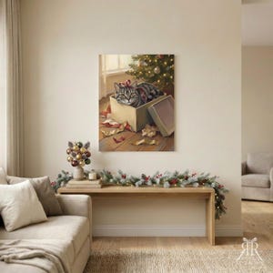May include: A square wall art print featuring a grey tabby cat sitting inside a cardboard gift box with a red ribbon on its head, positioned on a wooden floor near a Christmas tree with scattered wrapping paper and a detached box lid.