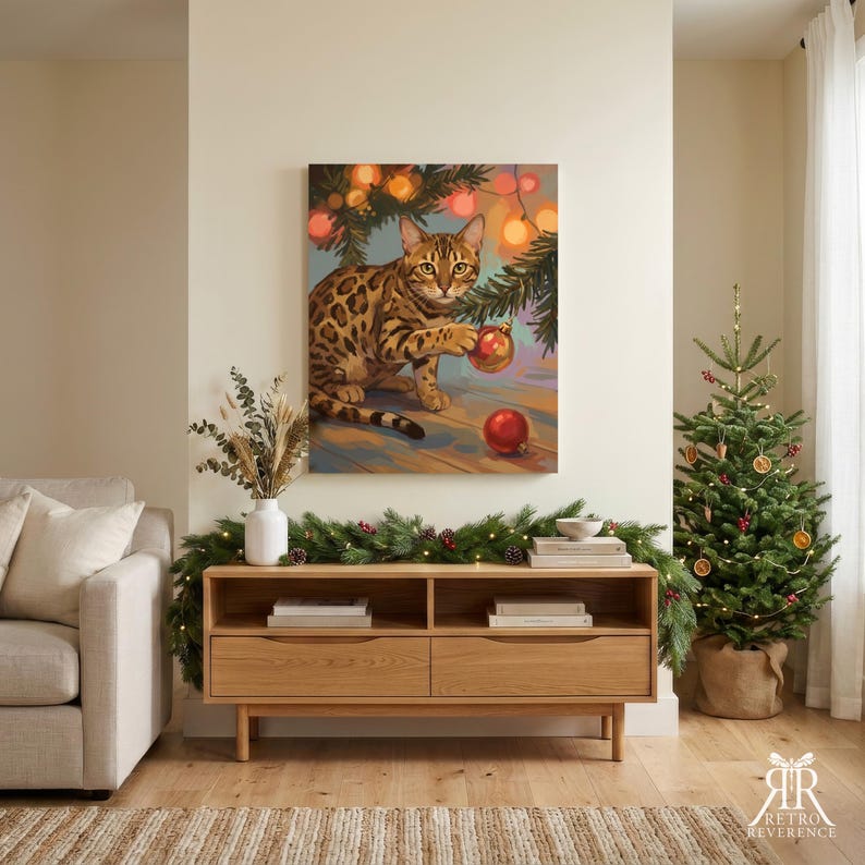May include: A square wall art print featuring a spotted Bengal cat sitting under pine branches, batting at a red Christmas ornament. The cat has golden-brown fur with dark spots. The background includes warm glowing lights and a red ornament on the floor.