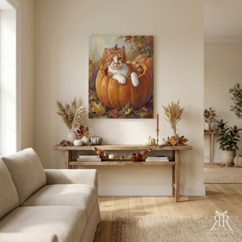 May include: A rectangular wall art print featuring an orange tabby cat sitting inside a large, round orange pumpkin surrounded by autumn leaves. The artwork displays warm fall colors and is displayed above a wooden console table with decor.