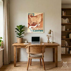 K&ouml;nnte beinhalten: Ein rechteckiges Wandposter mit einer getigerten, ingwerfarbenen Katze auf einem Holzboden, die eine Spur aus wei&szlig;em Toilettenpapier hinterl&auml;sst. Der Text lautet TOILET PAPER CANYON und Miles of scenic (and shredded) trails in Dunkelblau.