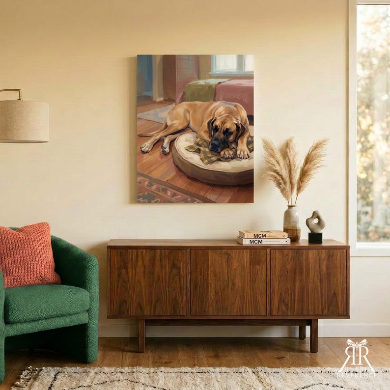 May include: A rectangular wall art print featuring a tan dog lying on a round beige cushion. The dog is positioned on a wooden floor within a room setting. The artwork is displayed on a light-colored wall above a wooden sideboard with books.