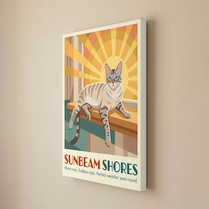 May include: A rectangular wall art print featuring a light brown tabby cat resting on a ledge against a yellow sunburst background. The text SUNBEAM SHORES is printed at the bottom, followed by the words Warm rays. Endless naps. Perfect weather year-round.