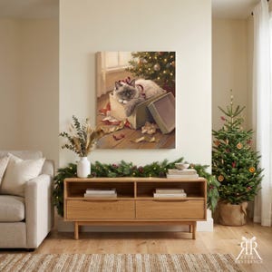 May include: A square wall art print featuring a fluffy ragdoll cat with a red ribbon around its neck, resting inside an open cardboard gift box. The scene is set on a wooden floor near a decorated Christmas tree with warm, glowing fairy lights.