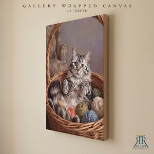 May include: A gallery wrapped canvas with a 1.5 inch depth featuring a painting of a grey and white tabby cat sitting inside a woven wicker basket filled with colorful balls of yarn. The text GALLERY WRAPPED CANVAS 1.5" DEPTH is visible above.