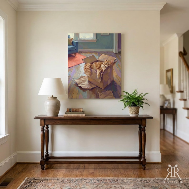 May include: A square wall art print depicting an orange tabby cat resting inside a cardboard box on a wooden floor. The painting features a blue chair and a red rug in the background, rendered in a painterly style with visible brushstrokes.